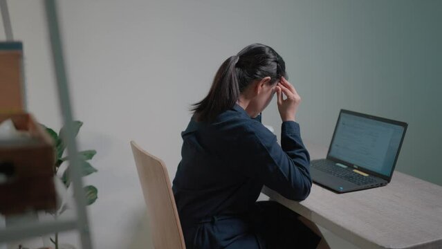 A female office worker who works in a hurry, typing quickly on a laptop computer. Before leaning back and stretching, feel your shoulders ache and relieve fatigue from sitting in a chair for a long ti