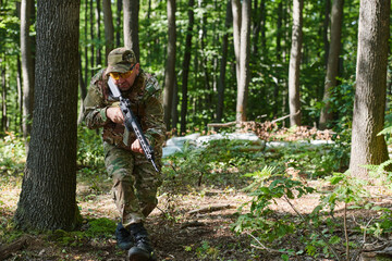 An elite soldier, camouflaged and stealthily navigating through dangerous woodland terrain,...