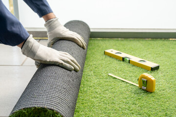 Man's hands spread an artificial turf roll at home