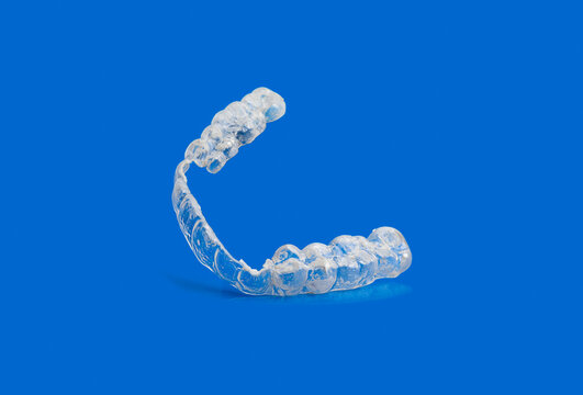 Worn and broken invisible orthodontic removable braces on blue background with copy space.Aligners for straightening of teeth