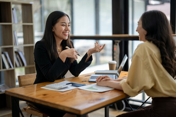 Two Asian businesswomen discuss financial management planning. Analyze new startup project ideas. Share an opinion