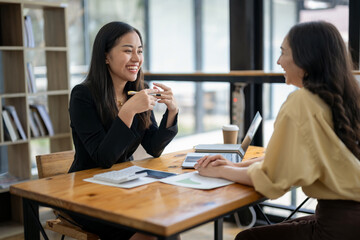 Two Asian businesswomen discuss financial management planning. Analyze new startup project ideas. Share an opinion