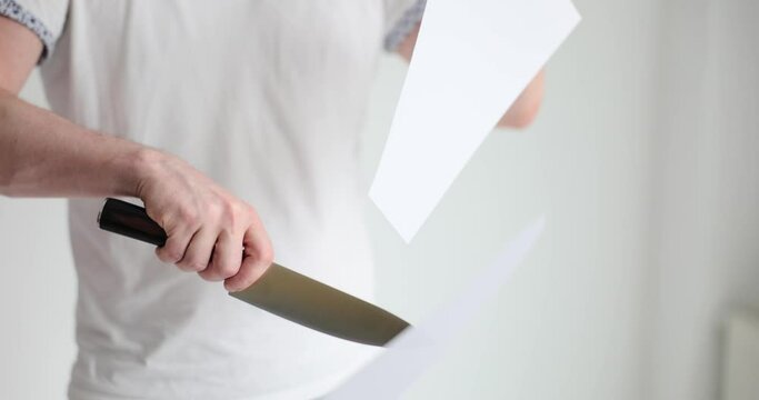 Cutting white paper with sharp knife. Man cutting paper