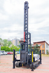 Construction platform on rubber crawler tracks with a winch, metal boom and vertical lifting mechanism.