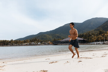 Muscular Asian Man Enjoying a Beach Run: Fitness and Freedom on Sand