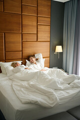 Blonde with her boyfriend are lounging on a large bed