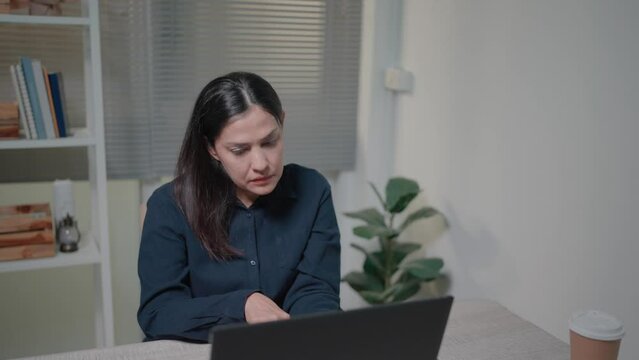Sad woman having financial problems or cash gap in business, throwing away pay check, sitting at table with laptop in home office
