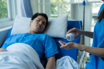 Young Asian male patient lying in bed while checking his pulse. Consult and explain with the nurse...