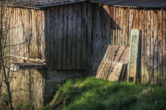 Holzh&uuml;tte mit Welldach und gelagerten Fensterladen und Schalbrettern auf Wiese
