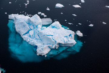 Top or aerial view of a huge iceberg floating in the dark blue sea in Antartica 