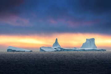 Iceberg swimming in the polar sea in front of midnight sun in Antarctica