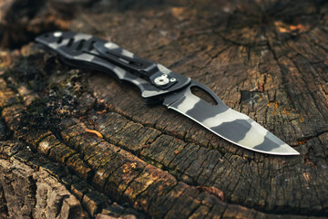 Folding knife on wooden background. EDC knife.