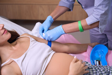 Cropped of female nurse preparing hand of young pregnant woman to injection