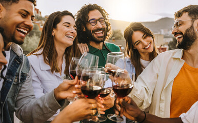 Happy friends toasting red wine glasses outside - Group of young people having bbq dinner party in backyard house - Winery and bbq dining concept with guys and girls cheering alcohol together - 721267525