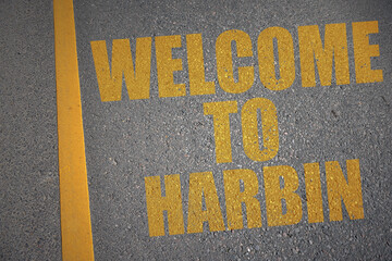 asphalt road with text welcome to Harbin near yellow line.