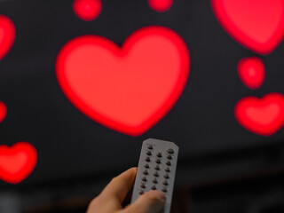 Pilot telewizora i ekran tv z włączonym filmem romantycznym, serduszka na ekranie - obrazy, fototapety, plakaty