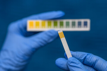 Trzymany w dłoni papierek lakmusowy do badania pH wskazujący na zakwaszenie organizmu