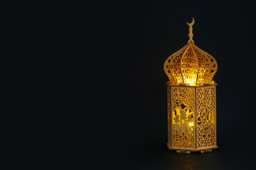 Golden shining wooden Ramadan lantern with Islamic carvings on a dark background. Happy Ramadan....