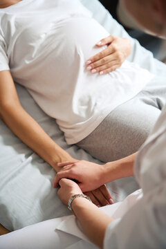 Partial image of female nurse holding hands of pregnant woman