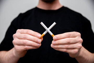 man holding two cigarettes creating a cross