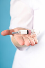 syringe for injection in the hands of a doctor on a blue background real context