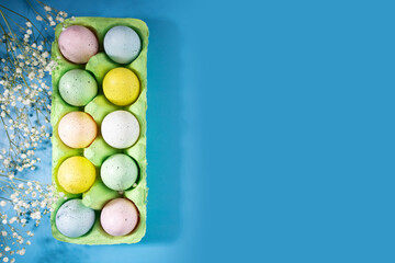 Easter eggs in a box and spring flowers on a blue background, festive decoration, holiday celebration, DIY