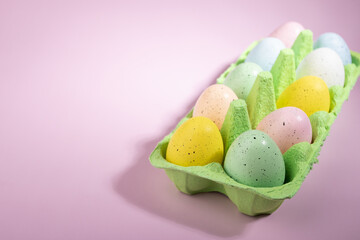 Decorative Easter eggs in a box, pink background, holiday celebration