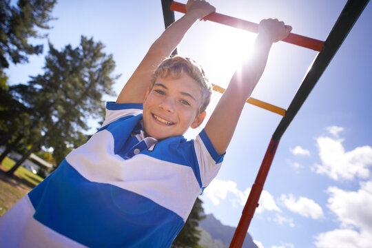 Child, monkey bars and park in portrait, smiling and energy at obstacle course on outdoor adventure. Happy male person, active and exercise on jungle gym, boy and fitness on playground in Australia