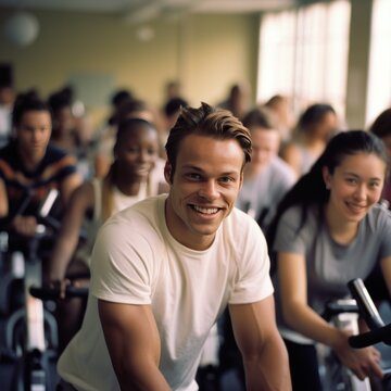 Fit people working out at spinning class in the gym, cycling a bike at gym, cardio training, exercising legs, wearing sports tights and top. Group of smiling friends at gym
