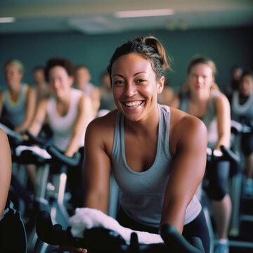 Fit people working out at spinning class in the gym, cycling a bike at gym, cardio training, exercising legs, wearing sports tights and top. Group of smiling friends at gym 