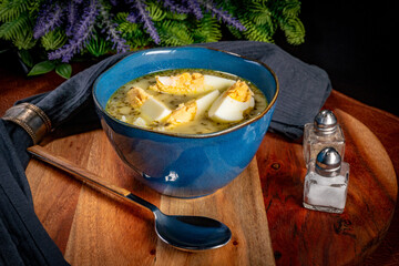 A bowl of soup sorrel with rice and boiled egg.