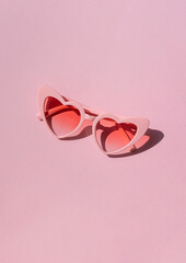 Heart shaped sunglasses on the pink background. Valentine's day concept composition