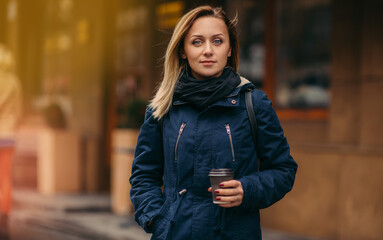 Stylish happy young woman holds coffee to go.