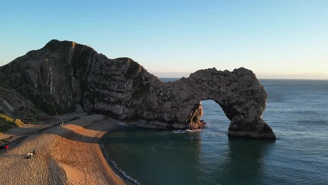 The sun goes down on the Jurassic coast and Durdle Door in Dorset with Seak Pink Trift growing on the top of the cliff in the foreground. Durdle Door, Dorset, Jurassic Coast, England, UK