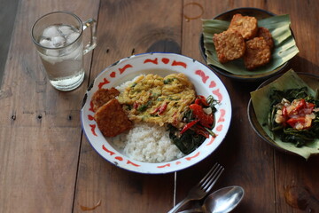 Nasi Rames Indonesian style lunch menu rice with fried egg, tempeh, and vegetables or tumis kangkung. Top View. 