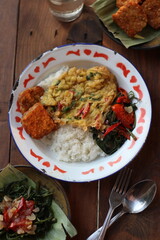Nasi Rames Indonesian style lunch menu rice with fried egg, tempeh, and vegetables or tumis kangkung. Top View. 
