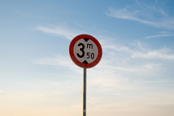 Height limit traffic sign, isolated sunset sky.