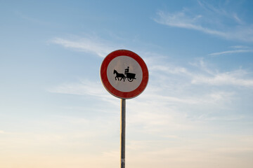 No entry for animal-drawn vehicles traffic sign, isolated sunset sky.