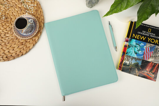 Leather pen and leather portfolio on desktop. with coffee and city guide image. nice desk top view. concept shot. Free space for mockup.. teal color.