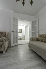 Interior in light colors with a bio fireplace, illuminated by burning sconces on the wall