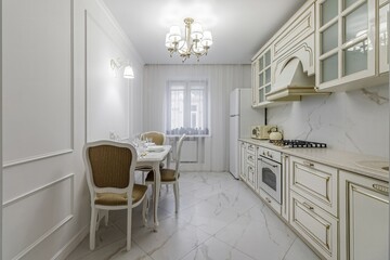 A beautiful kitchen detail with white cabinets, a gold faucet, white marble countertops