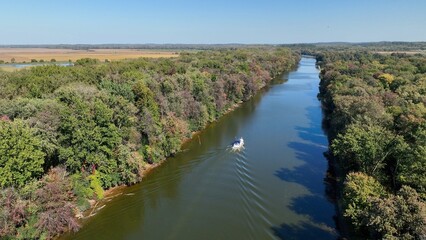 Fototapeta na wymiar Boat traveling through green landscape with Seneca River in up state New York at Montezuma Wildlife Refuge