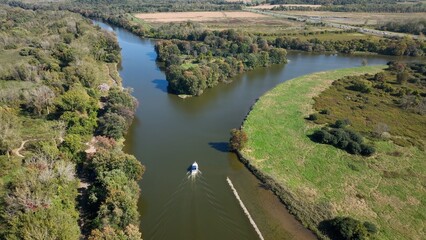 Fototapeta na wymiar Boat traveling through green landscape with Seneca River in up state New York at Montezuma Wildlife Refuge