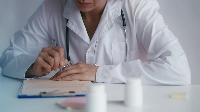Close-up of female physician prescribing medication, filling out rx form
