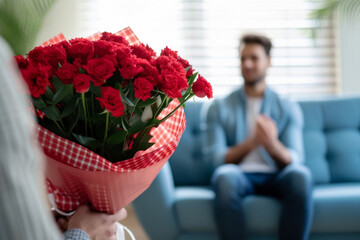 Red Flowers Gift in Home Setting.
A close-up of someone giving a bouquet of red flowers, with a man in the background at home.