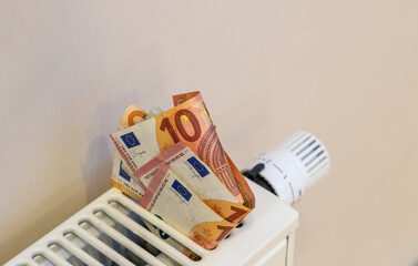 large sum of money in euros on a heating radiator. The concept of increasing prices for energy...