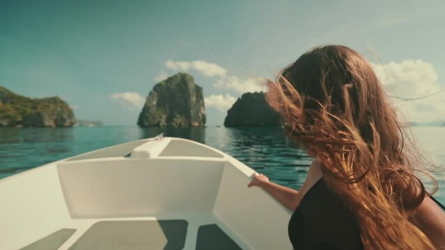 Girl sailing speed boat slow motion wind blow long hair. Young adult female enjoying fast ride on a motorboat. Feeling alive, and free concept. Travel holidays tour to Philippines, El Nido Islands.