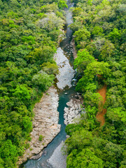 Blue jungle river next to orange road near natural reserve in Panama as drone view