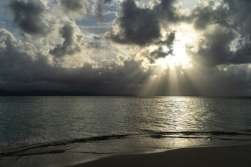 Golden sun rays shining through clouds hitting caribbean water surface