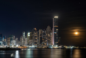 Fototapeta na wymiar Long exposure city skyline of Panama City at night with glowing moon as wallpaper